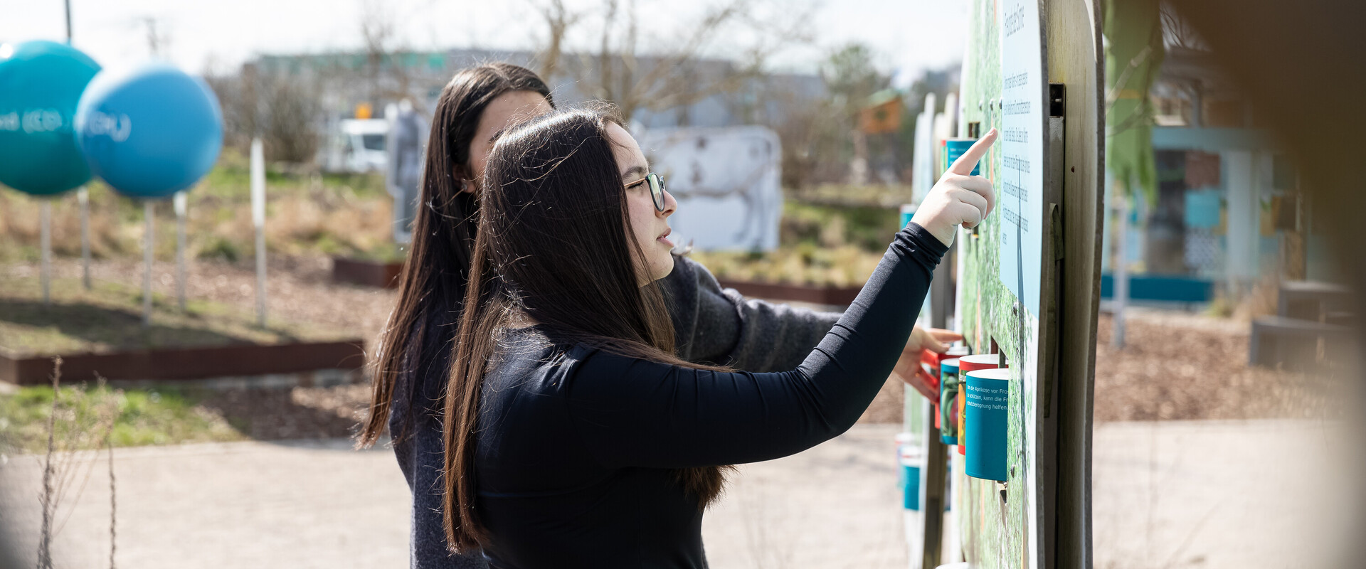 Sch&uuml;lerinnen bei einer schauen sich Ausstellungsstation im Au&szlig;enbereich der KLIMA ARENA an.